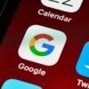Macro view of a smartphone displaying Google and other app icons on the home screen.