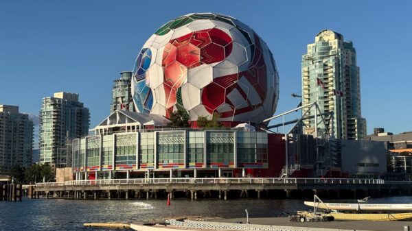 A massive soccer ball decorates Science World, set against Vancouver's iconic skyline and waterscape.