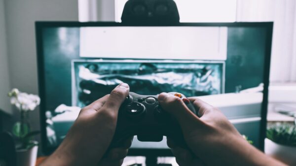person holding game controller in-front of television