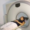 A woman lying inside an MRI machine during a medical procedure in a hospital setting.