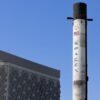 A SpaceX Falcon 9 rocket displayed outdoors against a clear blue sky in Dubai.
