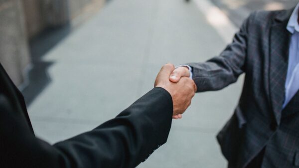 Close-up of two businessmen shaking hands outside, symbolizing partnership and agreement.