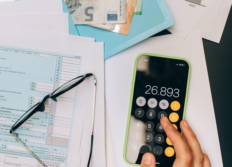 A top view of financial documents, calculator on smartphone, and euro notes, depicting business analysis.
