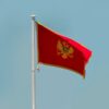 Vertical shot of the Montenegro flag waving against a clear sky in Podgorica.