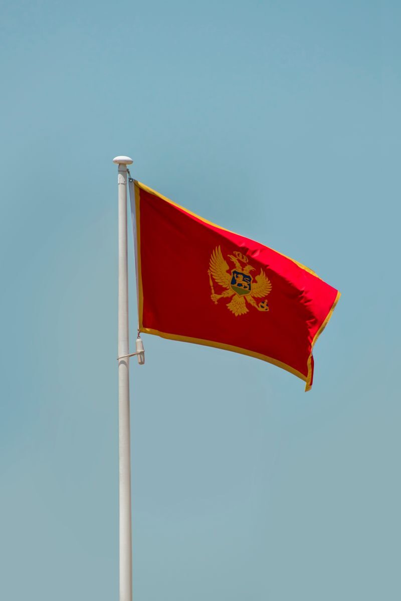 Vertical shot of the Montenegro flag waving against a clear sky in Podgorica.