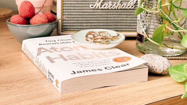 A book, fruits, and a vintage speaker on a cozy table setting indoors.