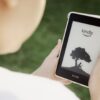 A child holds a Kindle device outdoors, highlighting the ease of reading with technology.