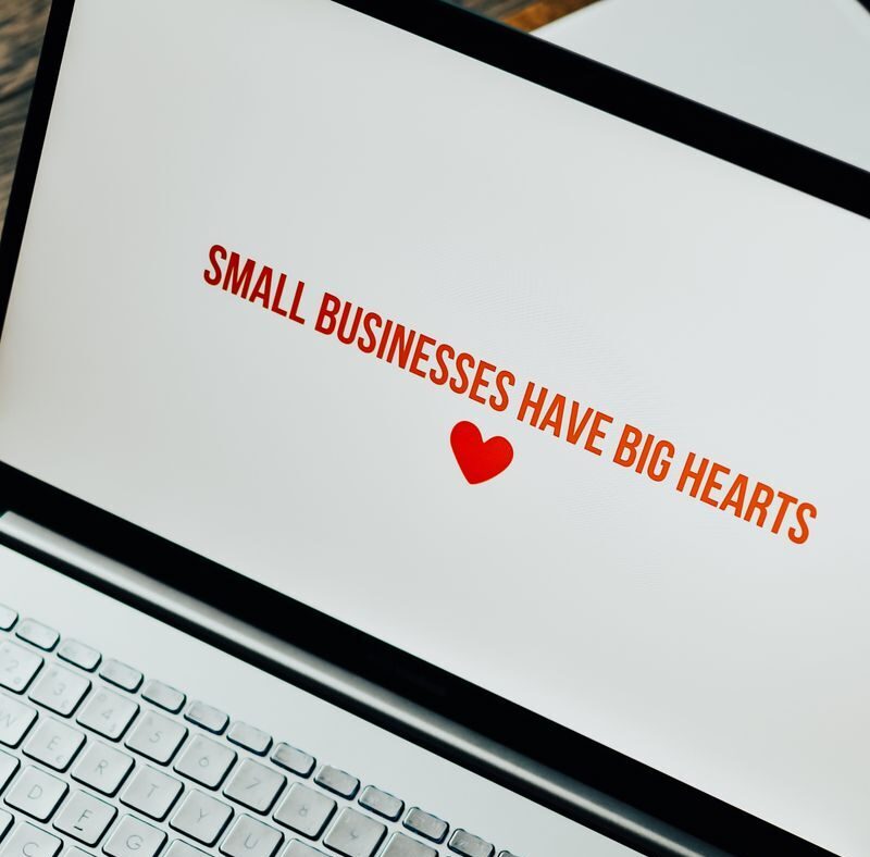 Close-up of laptop displaying 'Small Businesses Have Big Hearts' message with a heart icon.