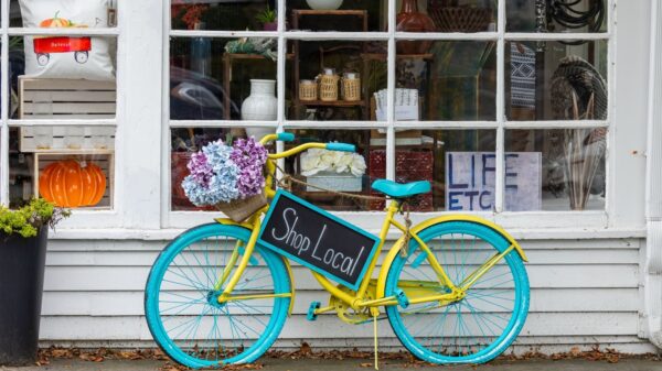 A colorful bicycle with flowers and 'Shop Local' sign outside a store in Sudbury, MA.