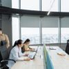 Contemporary office scene with Asian coworkers working on laptops and smartphones.