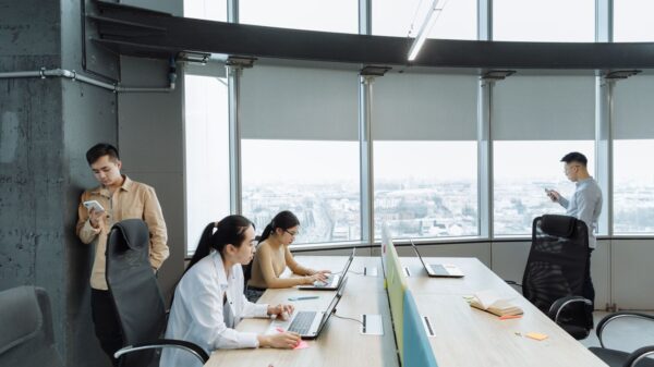 Contemporary office scene with Asian coworkers working on laptops and smartphones.