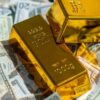 Close-up of gold bars atop US currency, symbolizing wealth and investment.