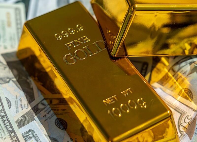 Close-up of gold bars atop US currency, symbolizing wealth and investment.