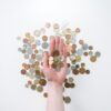 An open hand holds various coins on a white surface, symbolizing finance and currency exchange.