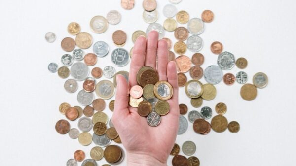 An open hand holds various coins on a white surface, symbolizing finance and currency exchange.