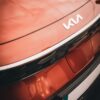 Stylish close-up of a red Kia vehicle's rear, showcasing the new logo design.