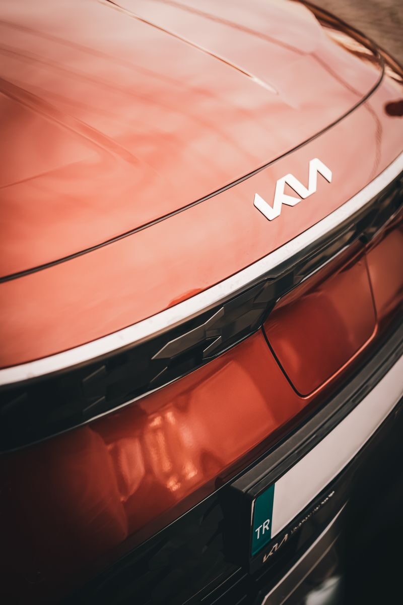 Stylish close-up of a red Kia vehicle's rear, showcasing the new logo design.