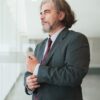 Businessman in a suit adjusting his cufflinks in a modern office space, exuding confidence.