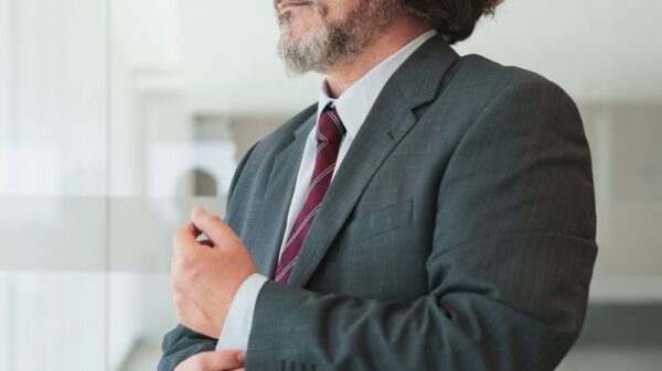 Businessman in a suit adjusting his cufflinks in a modern office space, exuding confidence.
