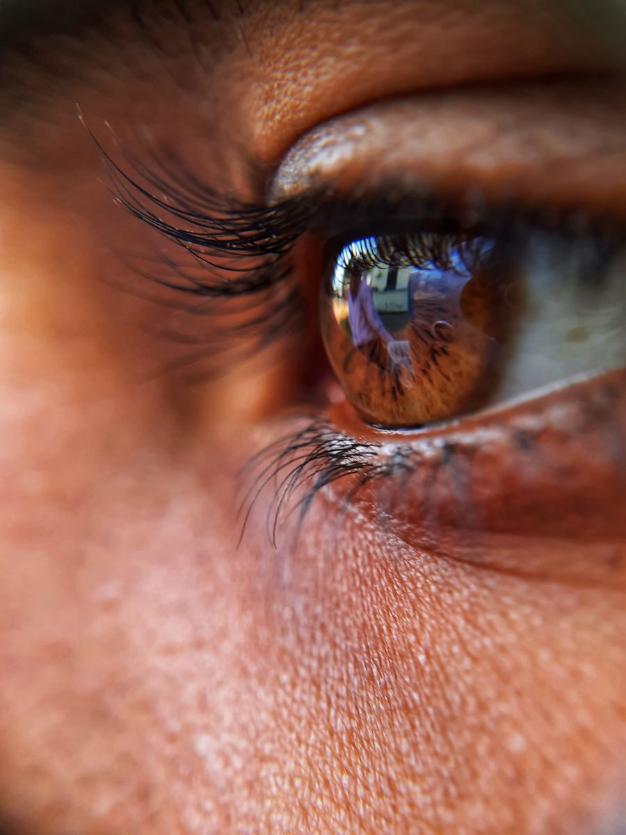 Detailed close-up of a brown eye reflecting a scene, showcasing texture and color.