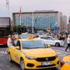 Yellow taxis and bustling street scene in front of a modern building in Istanbul, Turkey.