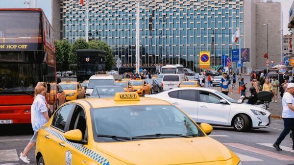 Yellow taxis and bustling street scene in front of a modern building in Istanbul, Turkey.
