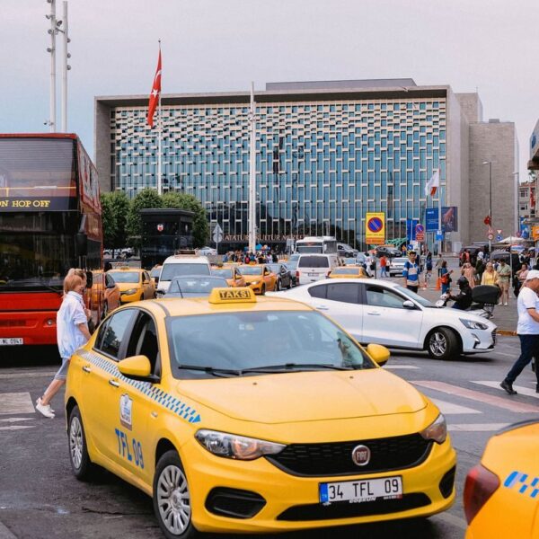 Yellow taxis and bustling street scene in front of a modern building in Istanbul, Turkey.