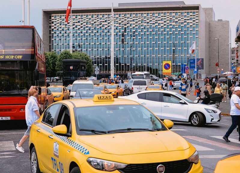 Yellow taxis and bustling street scene in front of a modern building in Istanbul, Turkey.