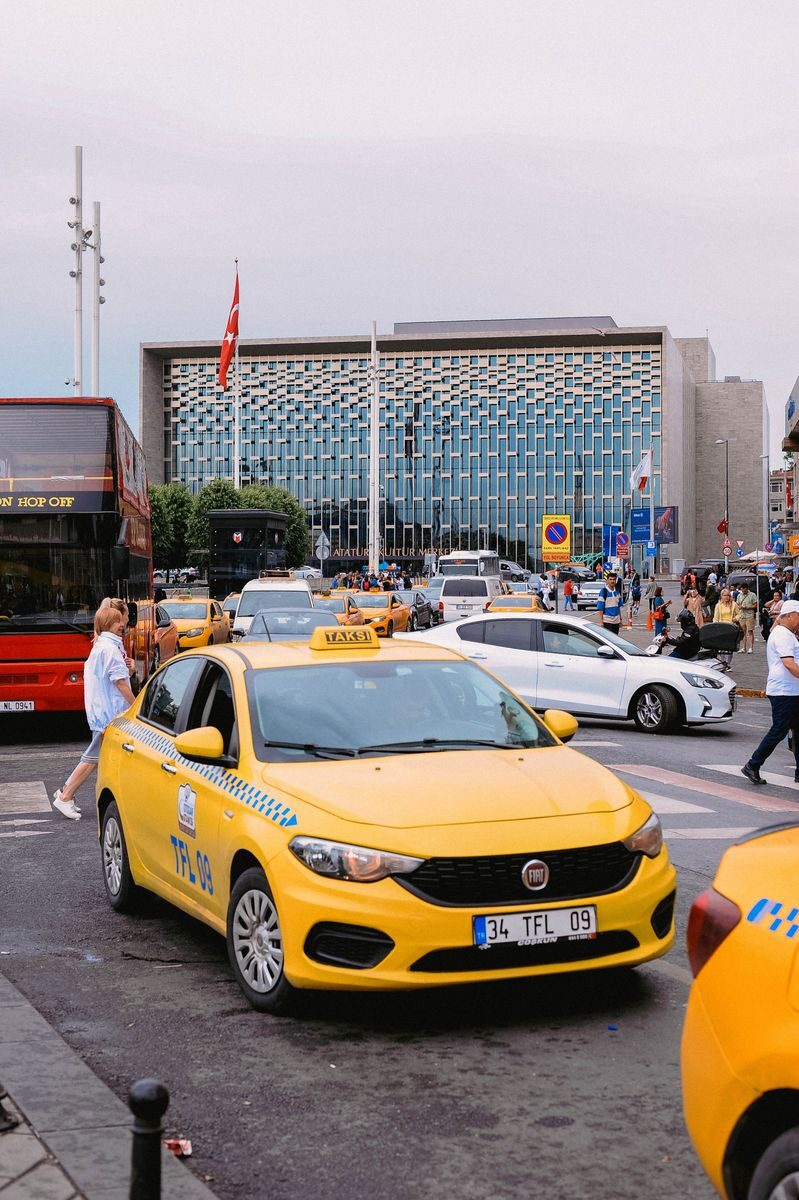 Yellow taxis and bustling street scene in front of a modern building in Istanbul, Turkey.