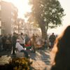 Crowded urban street scene in summer with people enjoying sunlit evening stroll.