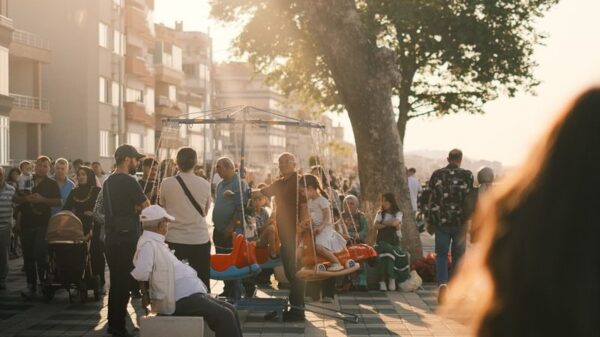 Crowded urban street scene in summer with people enjoying sunlit evening stroll.