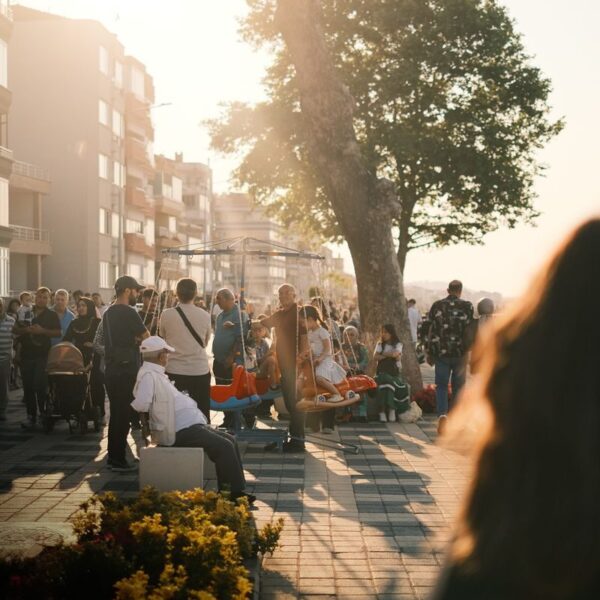 Crowded urban street scene in summer with people enjoying sunlit evening stroll.