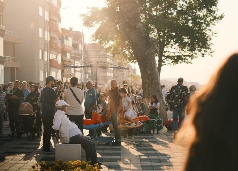 Crowded urban street scene in summer with people enjoying sunlit evening stroll.