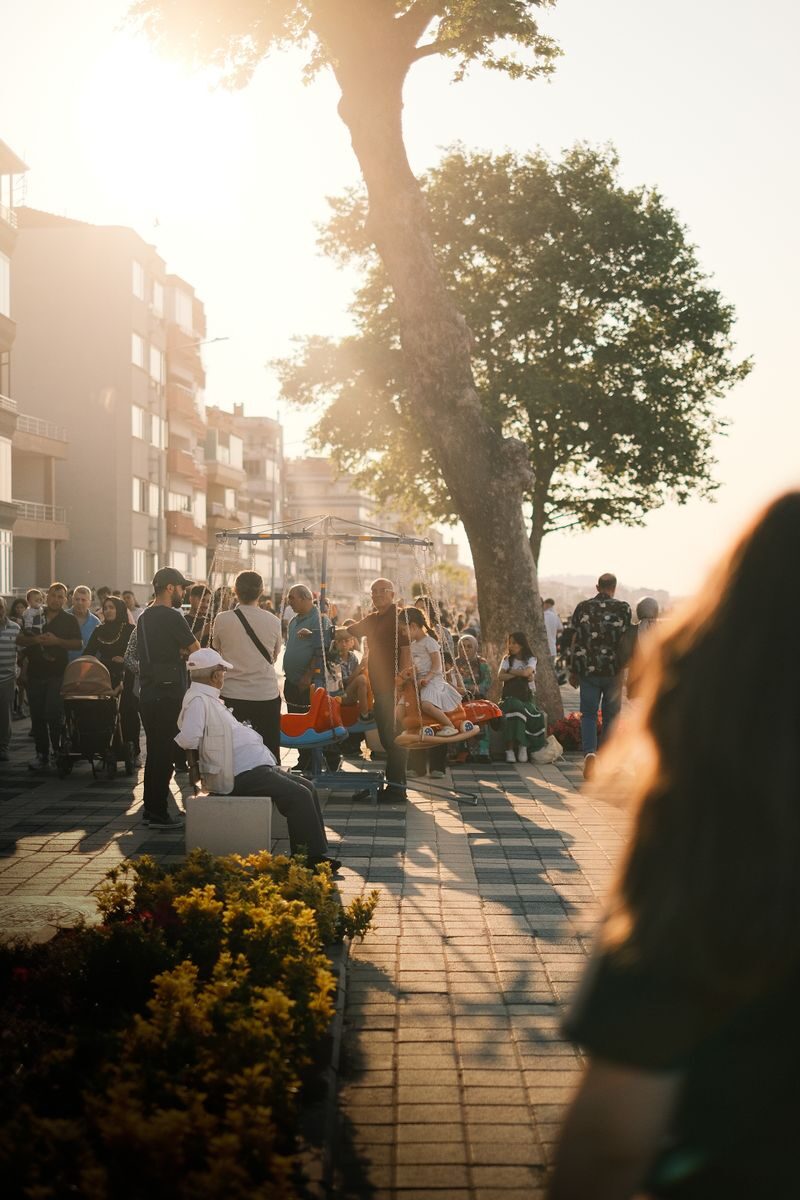 Crowded urban street scene in summer with people enjoying sunlit evening stroll.