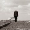 A man walks alone on railway tracks, symbolizing solitude and adventure.