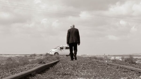 A man walks alone on railway tracks, symbolizing solitude and adventure.