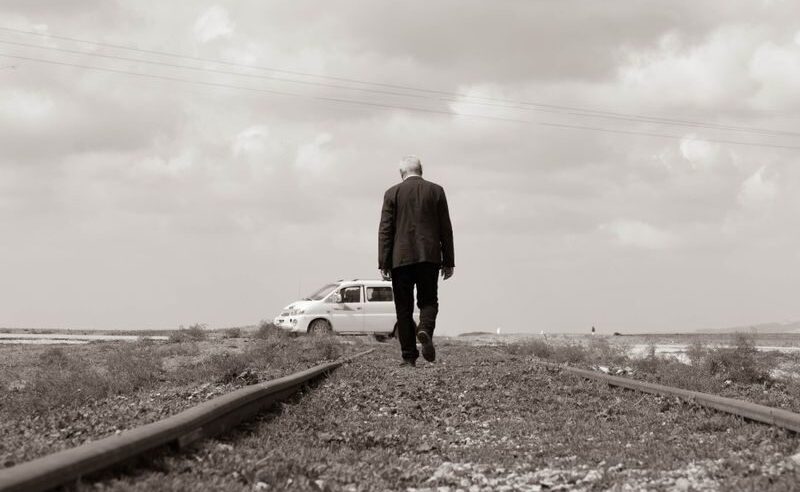A man walks alone on railway tracks, symbolizing solitude and adventure.