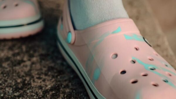Detailed view of pink Crocs worn with white socks on a textured surface.