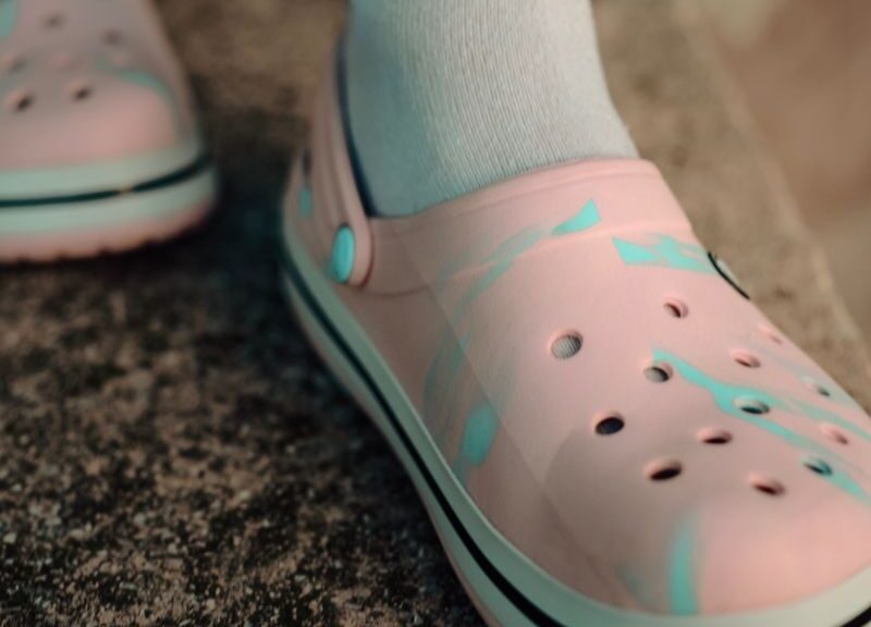 Detailed view of pink Crocs worn with white socks on a textured surface.