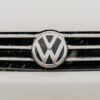 Closeup of a snow-dusted Volkswagen car grille shows the iconic VW logo.