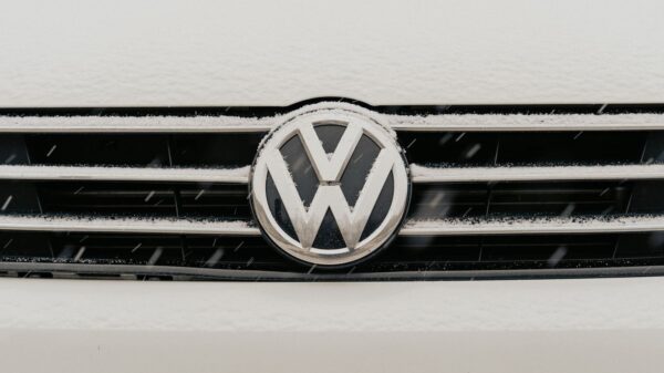 Closeup of a snow-dusted Volkswagen car grille shows the iconic VW logo.