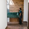A mover carries a green sofa indoors, showcasing modern interior design and relocation services.