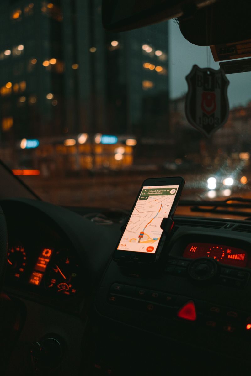 Car dashboard with GPS showing map on a digital screen during city driving at dusk.