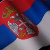 Close-up of the Serbian national flag showcasing its emblem and colors, symbolizing pride.