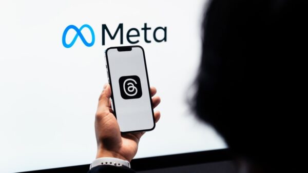 Hands holding smartphone with Meta Threads logo on screen, Meta branding in background.