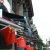 Historic street in China adorned with national flags and traditional Chinese architecture.