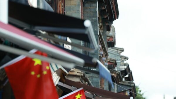 Historic street in China adorned with national flags and traditional Chinese architecture.