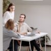 Three colleagues engage in a collaborative meeting around a table in a bright office space.