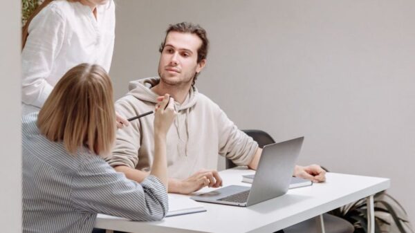 Three colleagues engage in a collaborative meeting around a table in a bright office space.