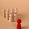 Wooden figures representing leadership and individuality on a neutral background.